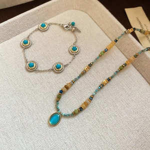 Detailed view of vintage beaded necklace and turquoise stone bracelet on a textured tray