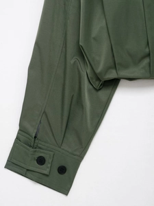 Detailansicht der Ärmelbündchen und des Saums einer dunkelgrünen Jacke mit Knöpfen