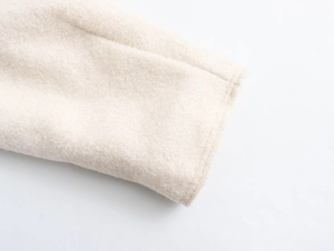 Détail d'une veste en bouclé blanc cassé montrant la maille et les coutures renforcées