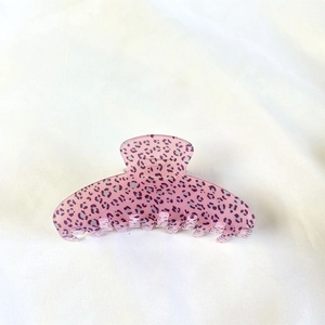 Macro shot of large pink and purple leopard print hair claw clip on white fabric