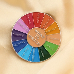 Close-up of circular film decision maker pin with colorful enamel movie genres on beige fabric