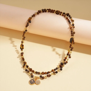 Detail of 18k gold plated necklace with tiger eye beads and rhinestone pendants