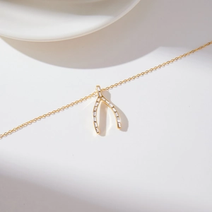 Détail macro du pendentif wishbone en acier doré 18K serti de zircons cubiques