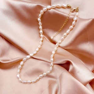 Macro detail of natural baroque pearls on pink silk with 14k gold-filled clasp