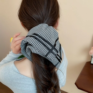Detail of black and white checkered oversized scrunchie on a ponytail with bow effect