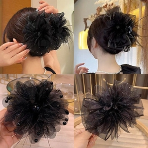 Detail showing elegant black mesh flower hair clip with beads and delicate feather accents