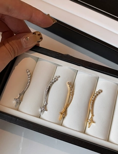 Detail shot of gold and silver star-shaped zircon earrings in a white jewelry box