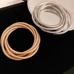 Close-up of three-layer stretch metal bracelets in gold and silver on black velvet