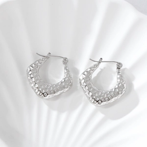 Gros plan détaillé de boucles d'oreilles en U argentées avec texture martelée élégante