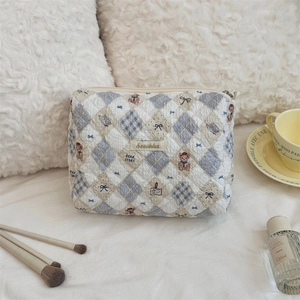 Gros plan d'une trousse à maquillage matelassée avec motif ours et étiquette tissée