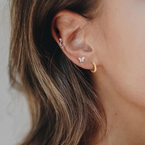 Detailed close-up of S925 sterling silver ear cuff and gold diamond hoop earring on ear