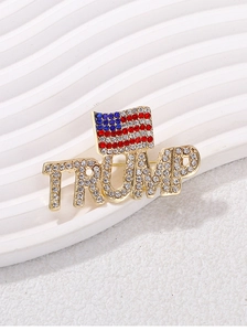 Close-up of golden TRUMP letter brooch with American flag and colorful rhinestones