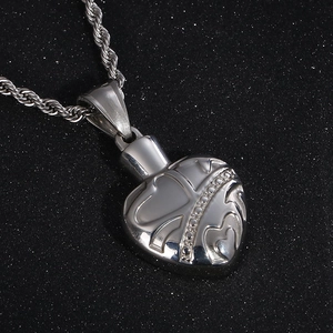 Close-up of a silver stainless steel heart pendant with embossed patterns and small diamonds