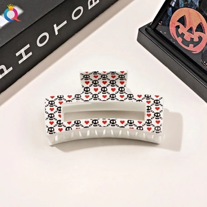 Detail of square Halloween hair claw clip with skull and heart print on cream base