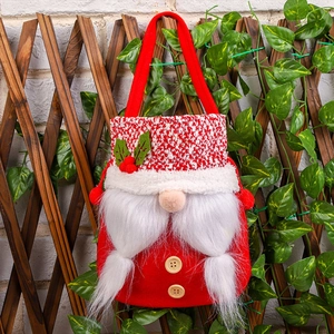 Christmas gnome gift bag with white beard and red knit hat hanging on a wooden fence