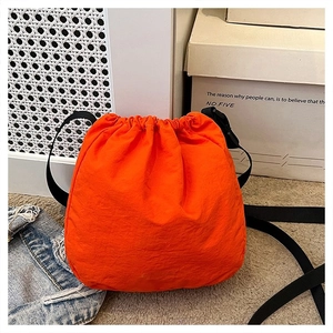 Detail view of the vibrant orange drawstring bucket bag with durable black straps
