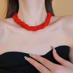 Dettaglio di una collana di perline rosse multistrato intrecciate indossata da modella