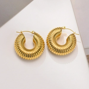 Detailed view of golden croissant hoop earrings with thick ribbed textured surface