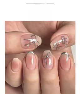Detail of pink gradient press-on nails with silver bows and sparkling rhinestone accents