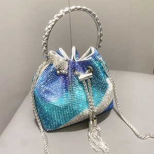 Dettaglio borsa a secchiello con strass sfumati blu e manico rotondo in metallo lucido