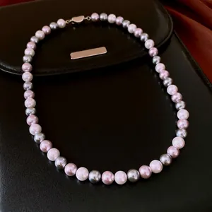 Elegant multi-colored pearl necklace with white purple and grey pearls on a black leather bag