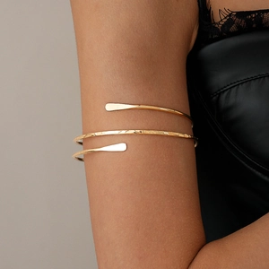 Detail of bohemian gold spiral arm cuff with hammered texture on a model's arm