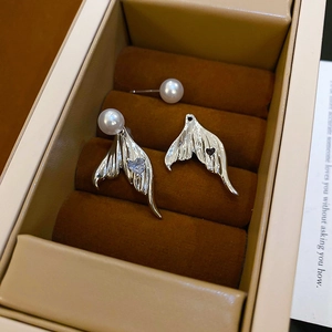 Macro view of mermaid tail earrings with heart zircon and pearl in a jewelry box