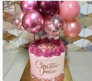 Close-up of pink and red metallic balloons with gold Christian Jenice cake topper