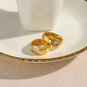 Detail of 18K gold plated stainless steel rings with square and marquise zircons on a plate