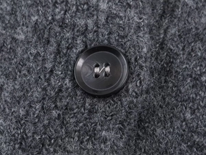 Macro view of dark grey knit texture with a black button on the cardigan detail
