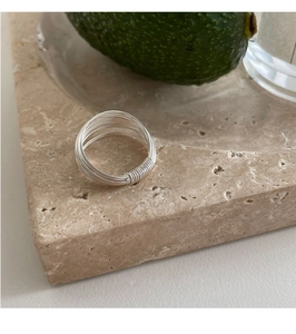 Detail of minimalist multi-layer silver wire wrap ring on a natural stone tray