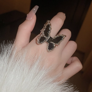 Close-up of a vintage butterfly ring with silver frame and black inlay on model's hand