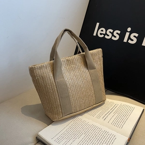 Macro detail of beige straw woven handbag with textured fabric handle in a minimal setting