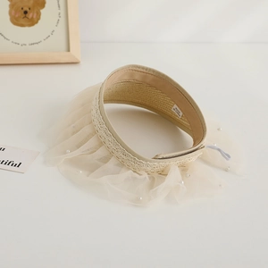 Close-up of beige straw sun visor with delicate lace trim and white pearl embellishments