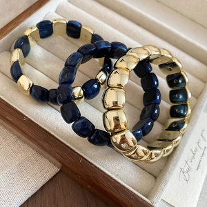 Detailed shot of dark blue marble resin beads and gold-plated elastic bracelets set