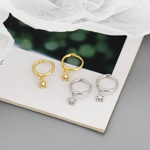 Close-up of gold and silver star earrings with cubic zirconia on white fabric