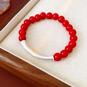 Vue macro d'un bracelet en perles rouges avec un accent de tube incurvé en argent
