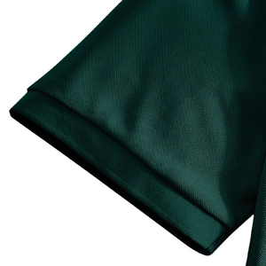 Close-up of the breathable dark green pique cotton fabric and knit cuff detail on polo shirt