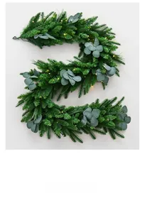 Detailed close-up of realistic pine needles and eucalyptus leaves with warm LED fairy lights