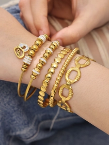 Détail de cinq bracelets en acier inoxydable plaqué or PVD avec zircons et pendentif cœur
