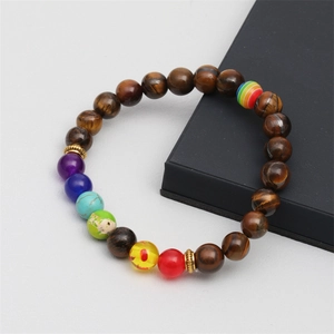 Gros plan d'un bracelet en perles d'oeil de tigre avec accents colorés et dorés