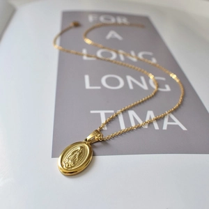 Gros plan détaillé d'un pendentif ovale Vierge Marie en or sur un collier vintage en acier