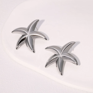 Minimalist silver starfish stud earrings in stainless steel on white stone background