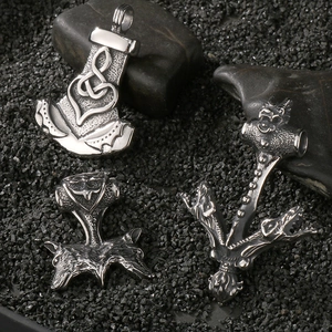 Macro shot of silver Viking Mjolnir pendants with wolf heads on dark stone background