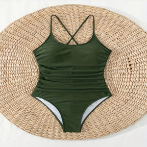 Flat lay of dark green one-piece swimsuit with spaghetti straps and ruched tummy control