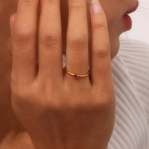 Detail showing an 18K gold plated thin ring with a red gemstone on a finger