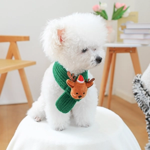 Close-up of green knitted pet scarf featuring a cute brown reindeer plush decoration
