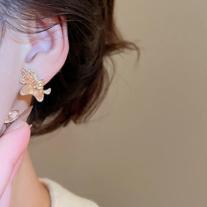 Close-up of 18k gold plated unicorn stud earring with crystals on model ear