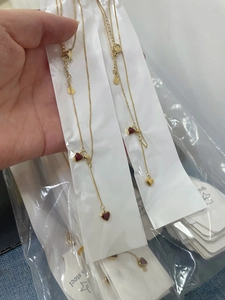 Detail shot of stainless steel gold chain necklaces with deep red heart pendants