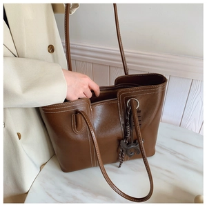 Close-up of brown leather tote with white contrast stitching and horse charm detail